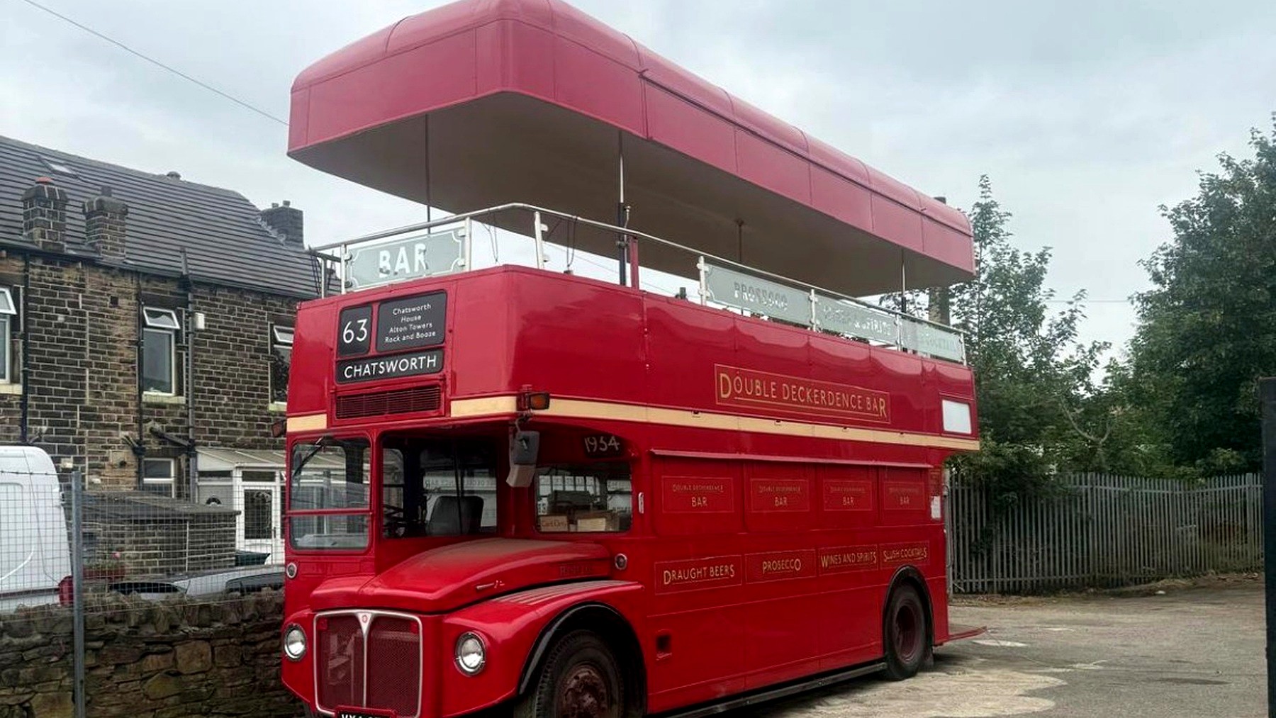 Converted red double-decker mobile bar with its roof raised