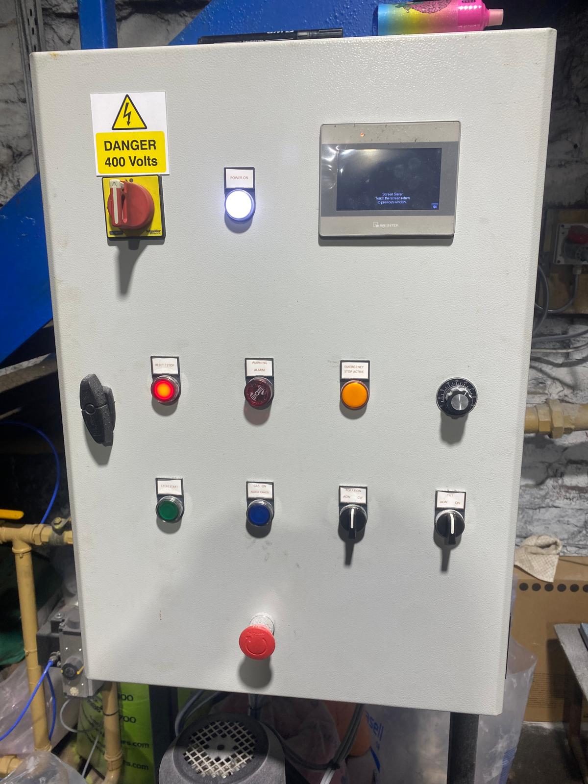 The installed panel combines an HMI touchscreen with physical switches, indicators and an emergency-stop button.
